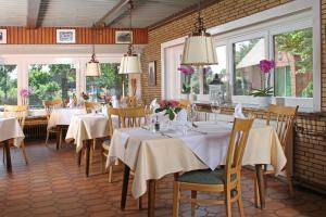 una sala da pranzo con tavoli, sedie e finestre di Haselauer Landhaus a Haselau