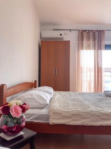 a bedroom with a bed with a vase of flowers on a table at Family Rooms in Ulcinj