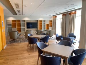 a waiting room with tables and chairs and a tv at Résidence Services Seniors Domitys - Les Safrans in Dives-sur-Mer