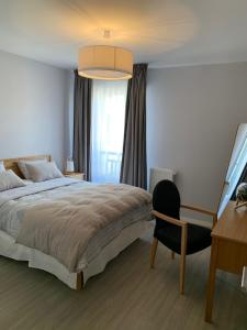 
a bedroom with a bed, chair, desk and lamp at Résidence Services Seniors Domitys - Les Safrans in Dives-sur-Mer
