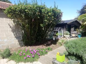 un jardin avec un arbre et des fleurs devant une maison dans l'établissement Le Gage location de vacance à la semaine, à Saint-Brévin-lʼOcéan