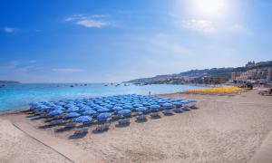 a group of blue umbrellas and chairs on a beach at Mellieha Holiday Centre in Mellieħa