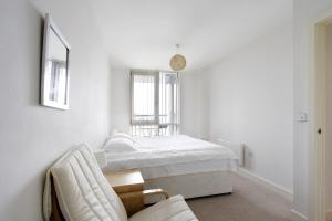 a white bedroom with a bed and a chair at Abodebed KD Tower in Hemel Hempstead