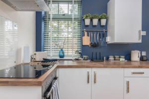 uma cozinha com armários brancos e uma parede azul em Rainbow House - Entire Place em Lutterworth