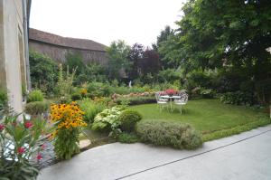 einen Garten mit einem Tisch, Stühlen und Blumen in der Unterkunft Chambre d'hôtes à TOUL centre ville avec parking privé in Toul