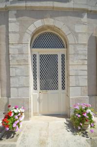 une porte dans un bâtiment en pierre avec deux fleurs dans l'établissement Chambre d'hôtes à TOUL centre ville avec parking privé, à Toul