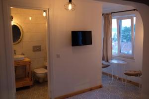 a bathroom with a toilet and a tv on the wall at 8 Pansiyon in Kaş