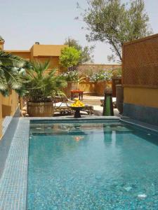 una piscina di fronte a un edificio con tavolo di Riad Ayadina & SPA a Marrakech