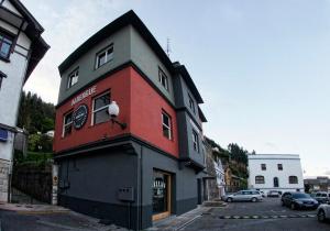 un edificio rojo y gris con un pájaro en la parte superior en Carving Surf Hostel, en San Esteban de Pravia