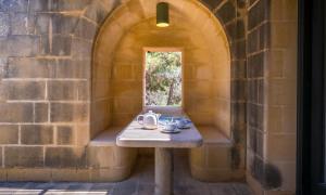 a table in a brick wall with two mugs on it at Mellieha Holiday Centre in Mellieħa