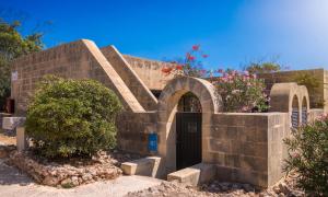 a brick building with a door and some flowers at Mellieha Holiday Centre in Mellieħa