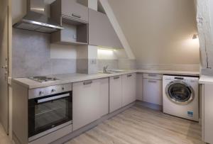 普羅萬的住宿－Residence The Originals Demeure des Remparts，厨房配有白色橱柜、洗衣机和烘干机
