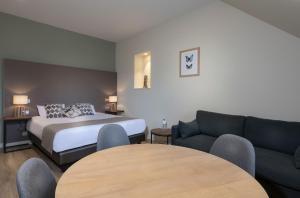 ein Hotelzimmer mit einem Bett, einem Sofa und einem Tisch in der Unterkunft Residence The Originals Demeure des Remparts in Provins