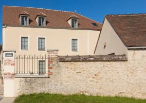 ein großes weißes Haus mit einer Steinmauer in der Unterkunft Residence The Originals Demeure des Remparts in Provins