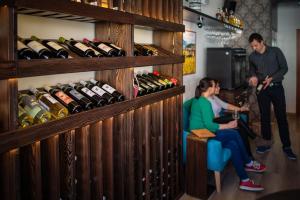 a woman sitting in a chair in front of a display of wine bottles at Penzion & Vinný bar Régio in Kyjov