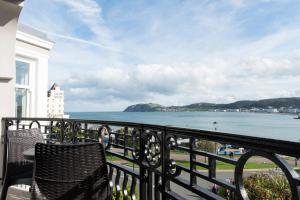 a balcony with two chairs and a view of the ocean at Belmont Llandudno in Llandudno