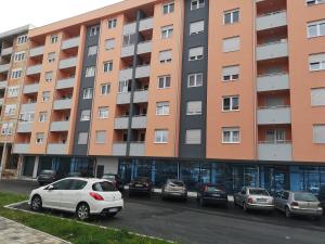 a large apartment building with cars parked in a parking lot at Apartman Gaga in Lukavica