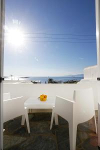Morfoula's Studios في مدينة ميكونوس: طاولة بيضاء وكراسي مطلة على المحيط