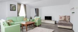 a living room with green chairs and a tv at Apartments Nasini in Plovdiv