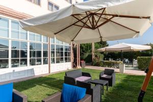 um pátio com uma mesa, cadeiras e um guarda-sol em Hotel Catullo em San Martino Buon Albergo