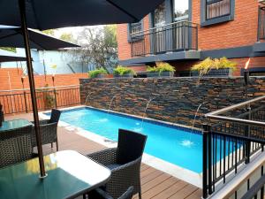 a table with an umbrella next to a swimming pool at Hotel AT Hatfield Apartments in Pretoria