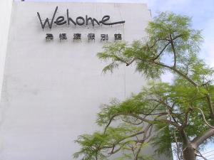 una señal en el lateral de un edificio con árboles en Wehome Motel, en Tainan