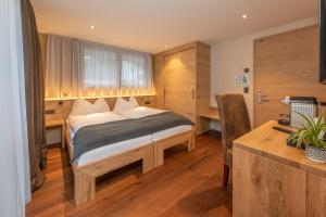 um quarto com uma cama e uma secretária num quarto em Hotel Heimatlodge em Sankt Niklaus