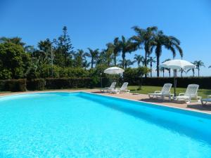 a swimming pool with chairs and umbrellas at Agriturismo La Grevillea in Riposto