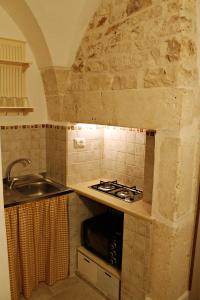 uma pequena cozinha com um fogão e um lavatório em B&B La Campanella em Putignano