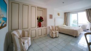 a bedroom with a bed and two chairs at Hotel Villa Fraulo in Ravello