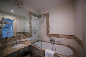 a bathroom with a tub and a sink and a mirror at Hotel Villa Fraulo in Ravello