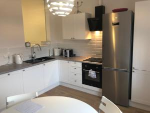 a kitchen with white cabinets and a stainless steel refrigerator at Apartament 'Laura' Tykocin in Tykocin
