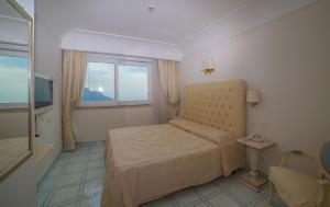 a small bedroom with a bed and a window at Hotel Villa Fraulo in Ravello