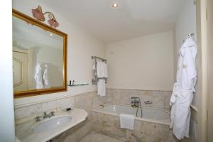 a bathroom with a tub and a sink and a mirror at Hotel Villa Fraulo in Ravello