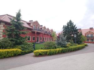 un gran edificio rojo con arbustos delante de él en Hotel Milord, en Pułtusk