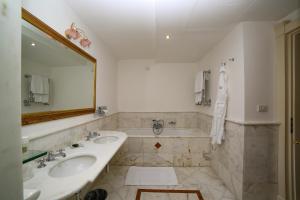 a bathroom with two sinks and a tub and a mirror at Hotel Villa Fraulo in Ravello