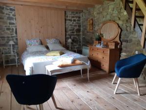 a bedroom with a bed and two chairs and a dresser at La Haute Gilberdière in Sartilly
