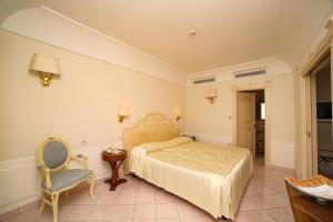 a bedroom with a bed and a chair at Hotel Villa Fraulo in Ravello