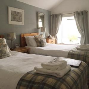 a bedroom with two beds with towels on top of them at Ardlogie Guest House in Aviemore