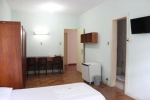 a room with a bed and a table and a kitchen at Hotel do CEE in Viçosa