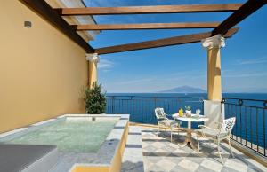 a patio area with chairs, tables, and a pool at Bellevue Syrene in Sorrento