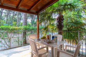 een tafel en stoelen op een veranda met een palmboom bij Villa Sofia in Rosolina Mare