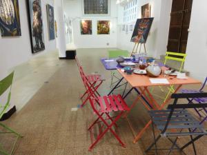 een tafel en stoelen in een kamer met schilderijen bij Studio au Centre d'Art ARKAD in Auvillar