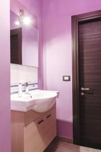 W łazience znajduje się umywalka, lustro i fioletowe ściany. w obiekcie B&B Raggio di Sole Porto Empedocle w mieście Porto Empedocle
