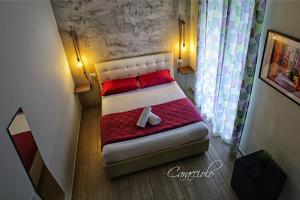 un piccolo letto in una piccola camera con rosso e bianco di Napoli City Rooms a Napoli