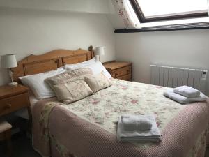 1 dormitorio con 1 cama con 2 toallas en Linhay -Farm Cottage, en Sidmouth