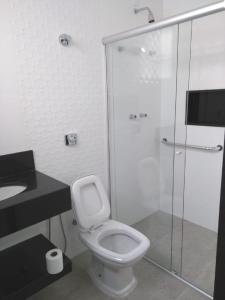 une salle de bain avec toilettes et douche en verre dans l'établissement Casa alto padrão Capitólio Lago Vitória, à Capitólio