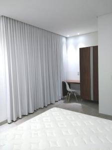 a room with a bed and a desk and curtains at Casa alto padrão Capitólio Lago Vitória in Capitólio