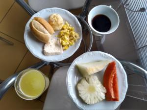 two plates of breakfast foods on a table with a cup of coffee at Tropical Palace Hotel in Lavras