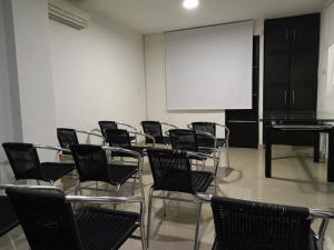 Habitación de clase con sillas y pantalla blanca en Hotel Santa Cecilia Cali, en Cali